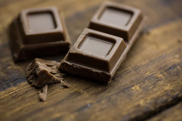 Pedazos de chocolate en una mesa de madera —  Fotos de Stock