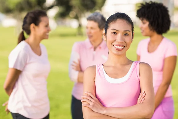 Smiling woman wearing pink for breast cancer in front of friends — Stock Photo, Image