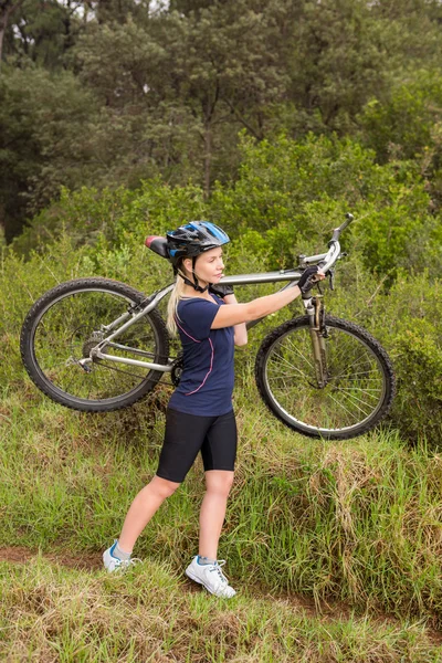 Rubia llevando su bicicleta de montaña — Foto de Stock
