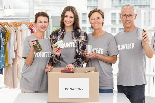 Lachende vrijwilligers tonen donaties — Stockfoto
