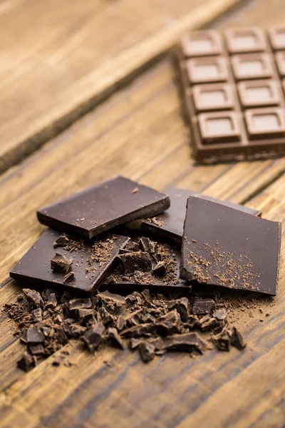 Bitar av choklad på ett träbord — Stockfoto