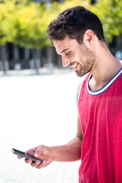 Handsome athlete sending a text — Stock Photo, Image