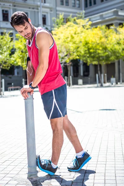 Atleta haciendo la pierna estirándose en una estaca —  Fotos de Stock