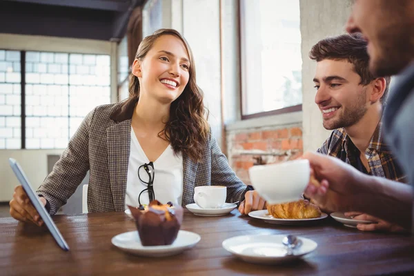 Amigos sonrientes disfrutando del café y el uso en la tableta — Foto de Stock