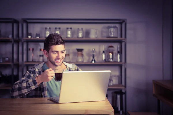 Hipster drinking coffee and using laptop — Stock Photo, Image