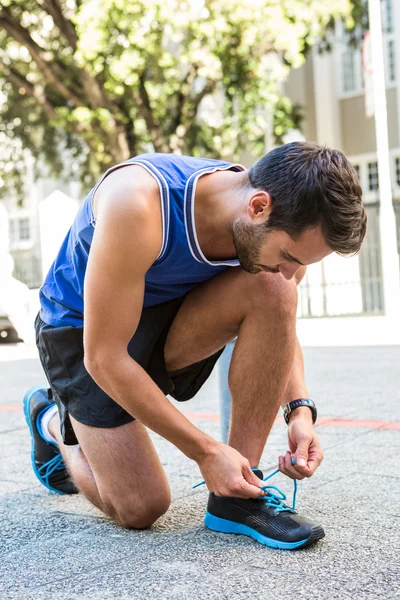 Knappe atleet koppelverkoop zijn schoen — Stockfoto