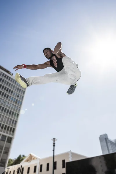 Atleta pulando na frente de edifícios — Fotografia de Stock