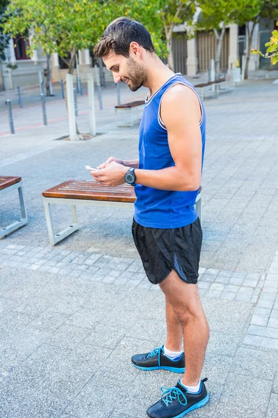 Atleta sorrindo e usando smartphone — Fotografia de Stock