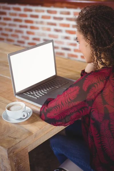 Brunette kop koffie met behulp van laptop — Stockfoto