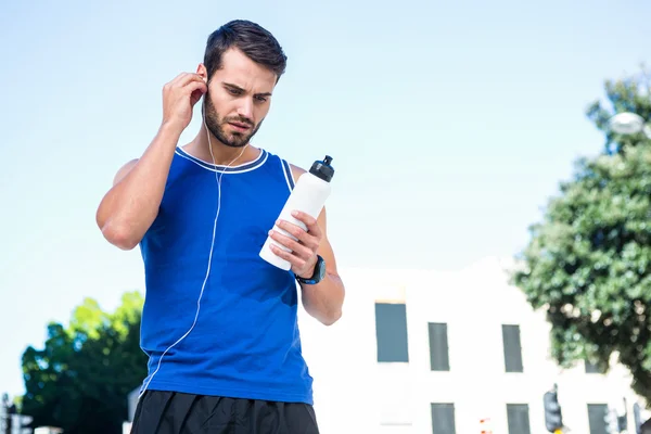 Handsome athlete looking at bottle — Stock Photo, Image