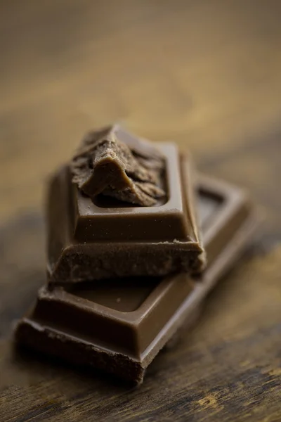 Stukken van chocolade op een houten tafel — Stockfoto