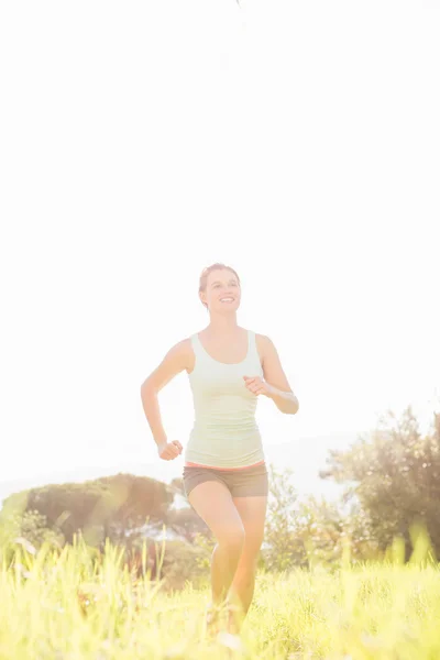 Blonde atleet joggen in gras — Stockfoto