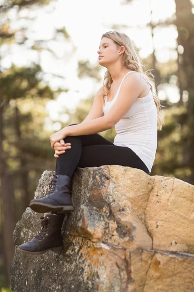 Junge Joggerin sitzt auf einem Felsen — Stockfoto