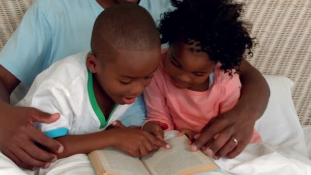 Padre e hijos leyendo en la cama — Vídeos de Stock