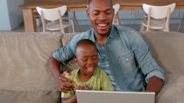 Vader en zoon met behulp van laptop op de Bank — Stockvideo