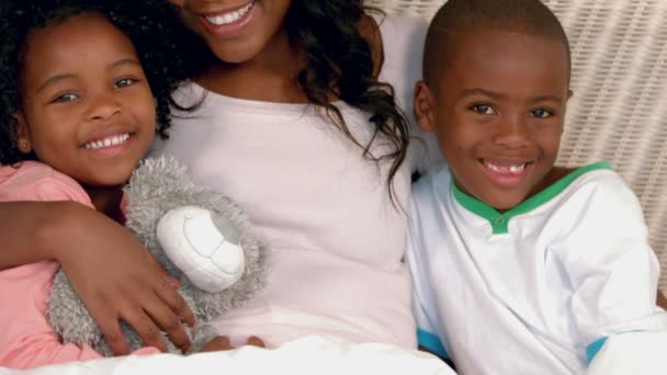 Madre e hijos sonriendo a la cámara en la cama — Vídeos de Stock