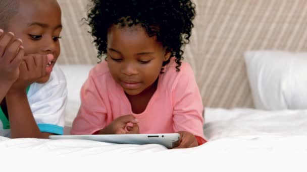 Hermanos felices usando tableta en la cama — Vídeos de Stock