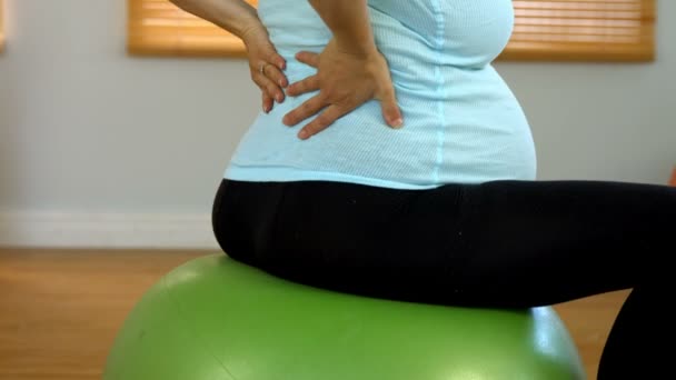 Gravid kvinna gnugga hennes nedre delen av ryggen — Stockvideo
