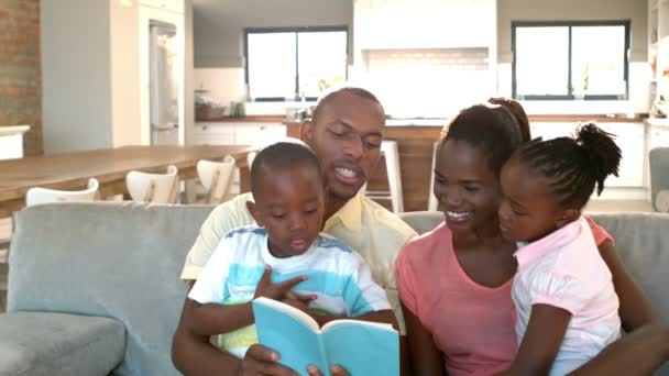Padres e hijos sentados en el sofá leyendo — Vídeo de stock