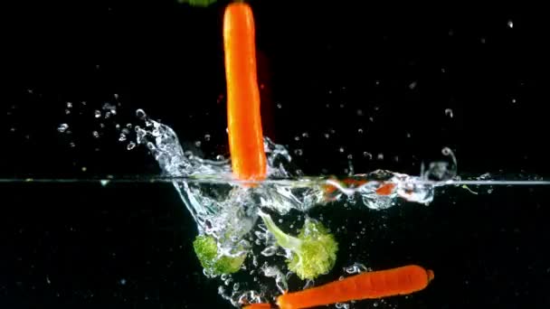 Brokkoli und Möhre fallen ins Wasser — Stockvideo