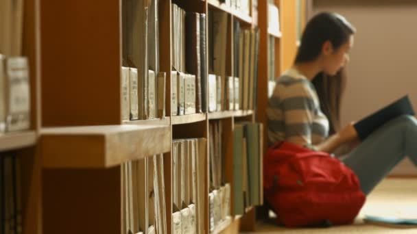 Estudiante leyendo un libro en la biblioteca — Vídeos de Stock