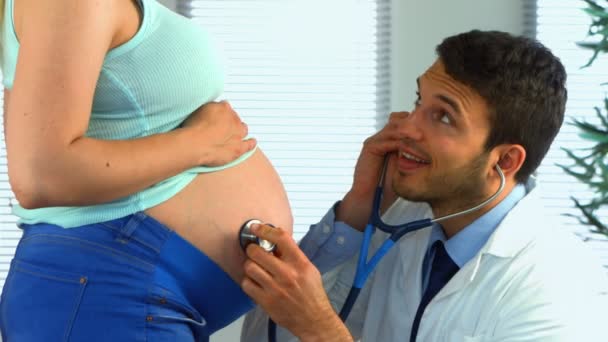 Läkaren lyssnar på en gravid kvinnas mage — Stockvideo