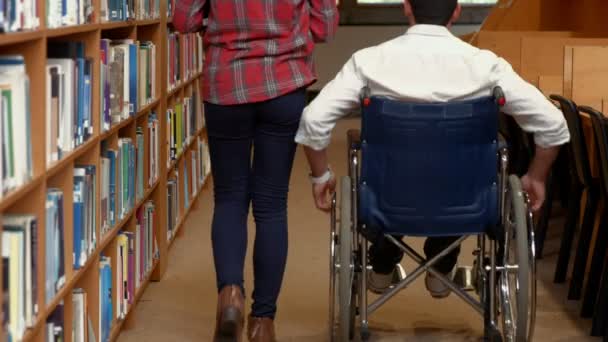 Студент та друг з обмеженими можливостями у бібліотеці — стокове відео
