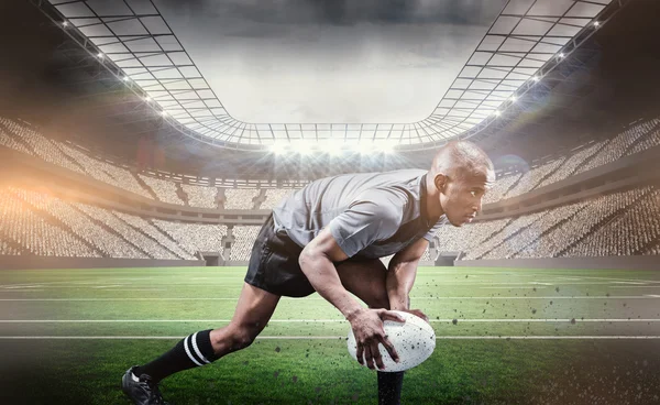 Friidrettsutøver som bøyer seg mens han spiller rugby – stockfoto