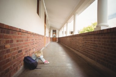 Sad pupil sitting alone on ground clipart