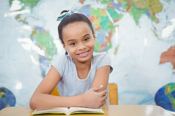 Lächelnder Student mit Buch auf dem Schreibtisch — Stockfoto