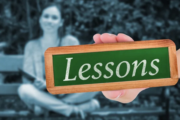 Lessons against smiling student sitting on bench listening music — Stock Photo, Image