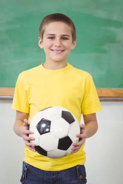 Lachende leerling voetbal houden in een klaslokaal — Stockfoto