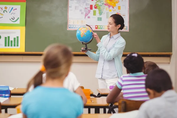 Pupil mendengarkan guru memegang bola dunia — Stok Foto