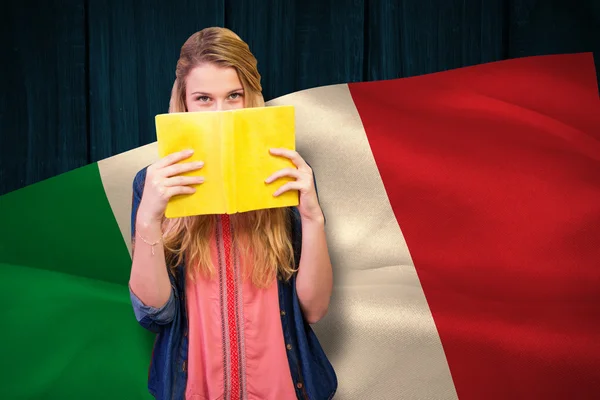 Student covering face with book in library — Stock Photo, Image