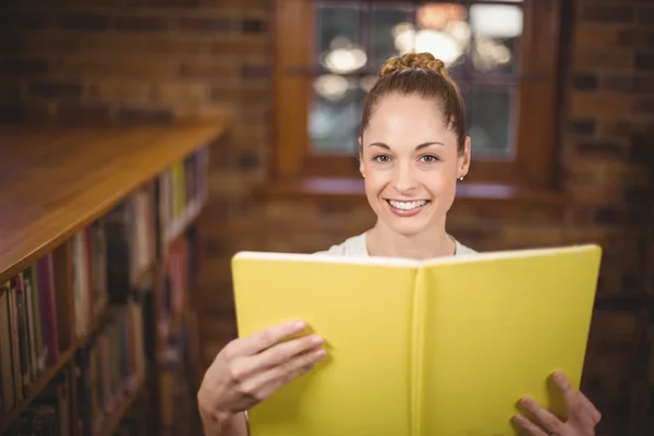 Blonde leraar lezing boek in de bibliotheek — Stockfoto