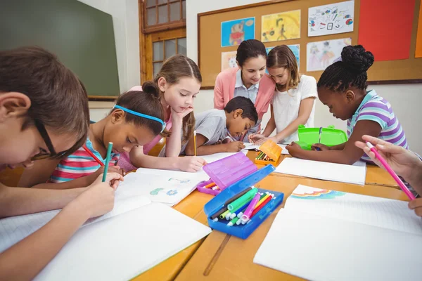 Teacher and pupils working at desk — Stock Photo, Image