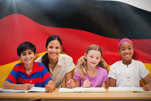 Imagem composta de professor bonito ajudando alunos na biblioteca — Fotografia de Stock