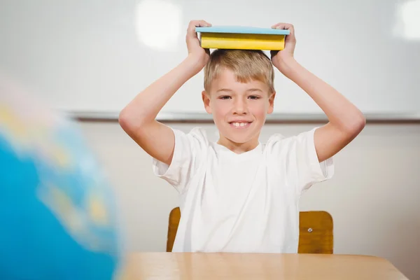 Leerling bedrijf boek over zijn hoofd — Stockfoto