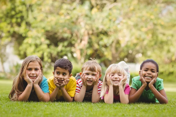 Lachende klasgenoten liggen in gras — Stockfoto