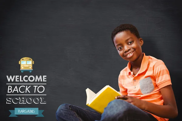 Cute boy reading book in library — Stock Photo, Image