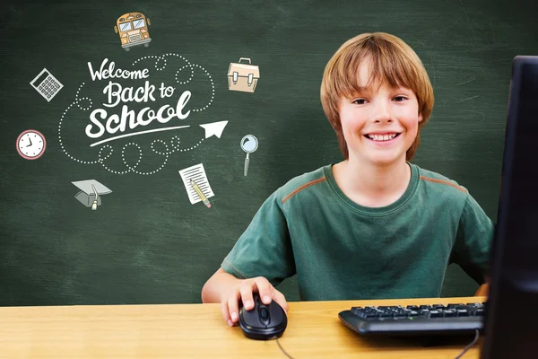 School kid working on computer against chalkboard — Stock Photo, Image