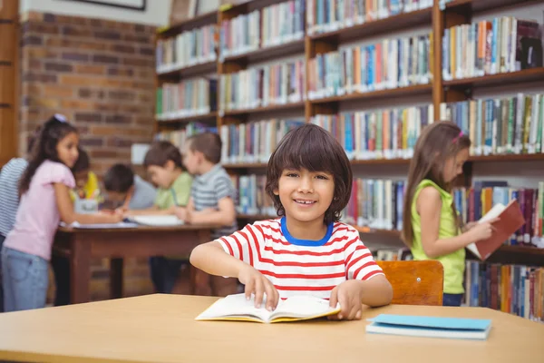 Ученик улыбается перед камерой в библиотеке — стоковое фото
