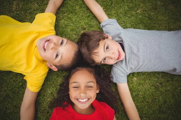 Carino alunni sdraiati su erba sorridente — Foto Stock