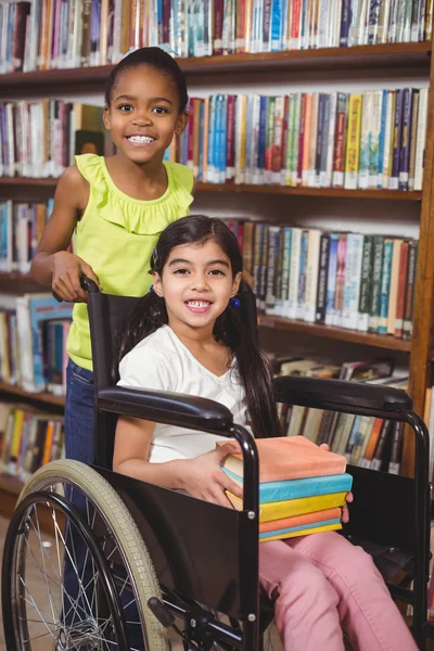 Élève souriant en fauteuil roulant tenant des livres — Photo