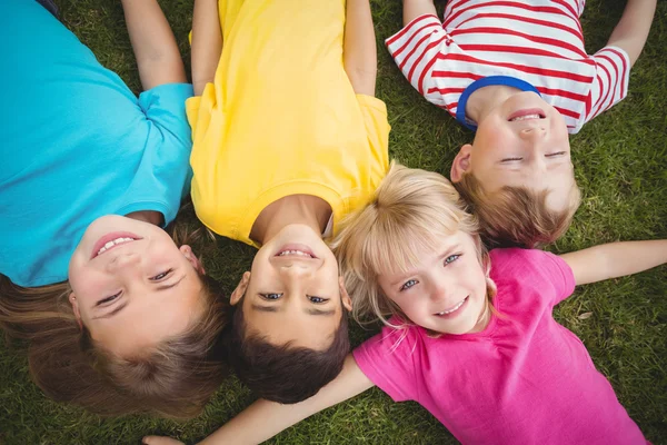 Des camarades de classe souriants allongés dans l'herbe — Photo