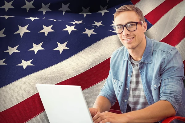 Hipster på laptop mot amerikanska flaggan — Stockfoto