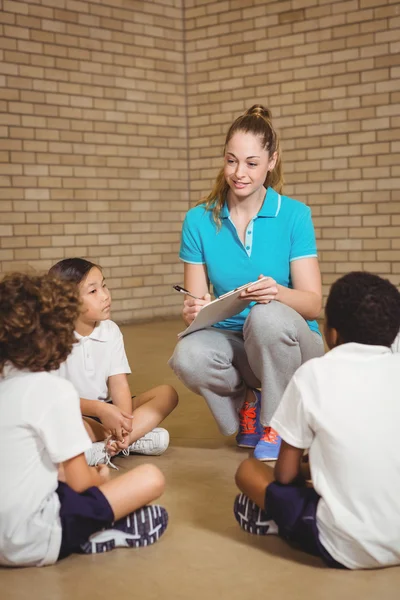 Teacher writing onto clipboard with students — Stock Photo, Image