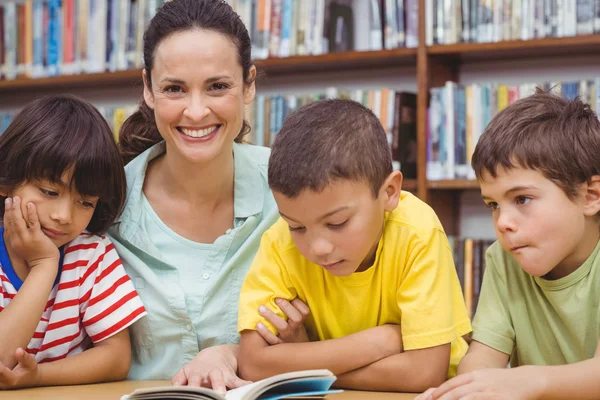 Alumnos y profesores leyendo libro en biblioteca — Foto de Stock