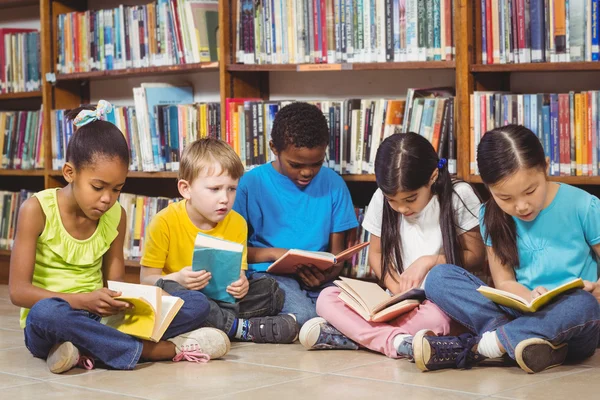 Alumnos que leen libros en la biblioteca — Foto de Stock