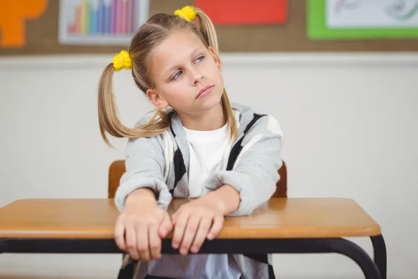 Élève réfléchie assise à son bureau dans une salle de classe — Photo